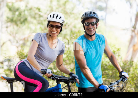 Coppia sorridente e in posa con le loro biciclette Foto Stock