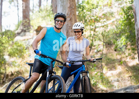 Coppia sorridente e in posa con le loro biciclette Foto Stock