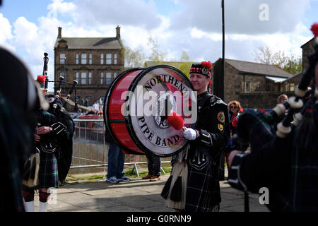 Northenden pipe band, vestito in kilts e uniforme con un batterista in azione al di fuori nei pressi di cornamusa. Foto Stock