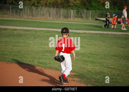 Carino little League Baseball lettore camminando sul campo da dietro. Foto Stock