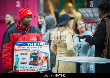 New York Times Square rosso vendita uniforme hop on off biglietti autobus temolo rappresentante Coach tours venditore con segno arresto Foto Stock