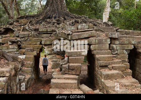 Tourist sotto albero che cresce sulle rovine di antichi Thmor Spean Bridge, Angkor Sito Patrimonio Mondiale, Siem Reap, Cambogia (MR) Foto Stock