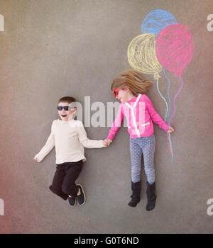 I bambini sono tenendo le mani al di fuori con colorati chalk palloncini delineato sul cemento per un creativo, artigianali o il concetto di riproduzione Foto Stock