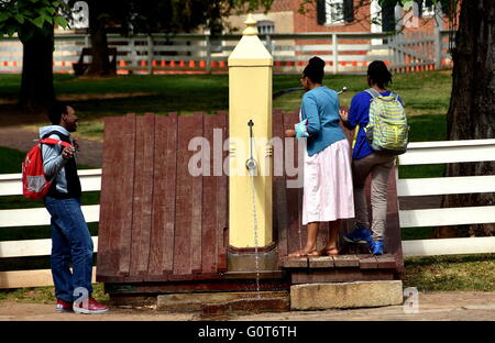 Vecchia Salem, North Carolina: tre studenti check out di una vecchia in legno pompa acqua sulla strada principale Foto Stock