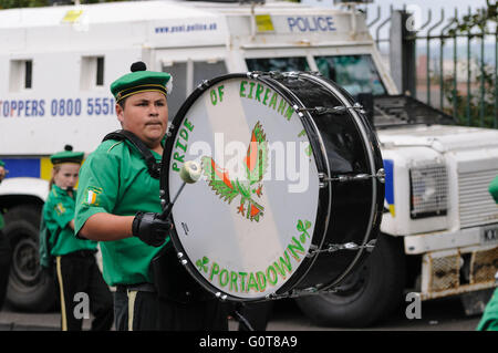 Un membro di un repubblicano irlandese flauto band suona un bass drum mentre passa un PSNI Landrover. Foto Stock