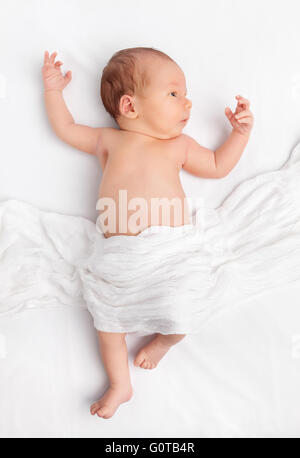 Carino neonato sdraiato sul letto sotto una coperta Foto Stock