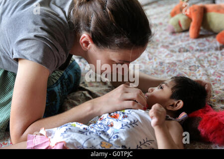 Volontari mentalmente la cura dei bambini malati in 'Nirmala Shishu Bhawan Childrens Home' delle Missionarie della Carità (Madre Teresa sorelle) in Calcutta, India Foto Stock