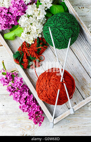 Palle di filati di lana per maglieria e rami di fiori lilla Foto Stock