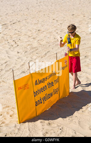 Bournemouth Dorset, Regno Unito il 5 maggio 2016. Bagnino di salvataggio mettendo banner di sicurezza sempre nuotare tra il giallo e il rosso bandiere a Bournemouth Beach Credito: Carolyn Jenkins/Alamy Live News Foto Stock