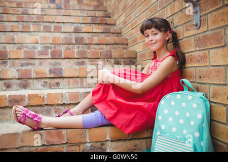 Sorridente schoolgirl seduto in scale Foto Stock