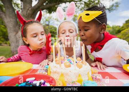 Tre bambine soffiando insieme candeline di compleanno Foto Stock