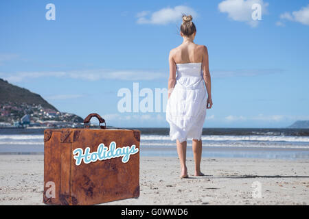 Immagine composita della bionda in abito bianco di camminare sulla spiaggia Foto Stock