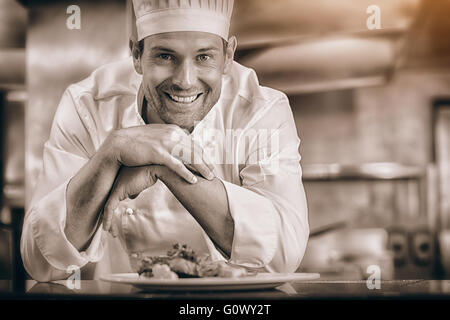 Sorridente chef maschio con cibi cotti in cucina Foto Stock