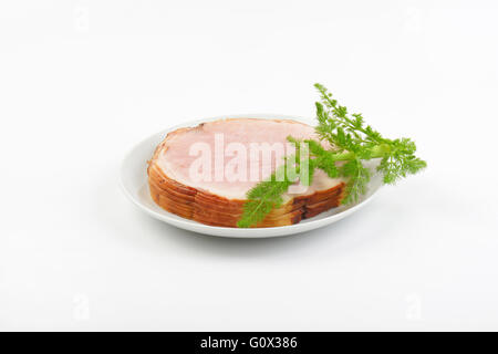 Pila di fette di prosciutto e aneto sulla piastra bianca Foto Stock