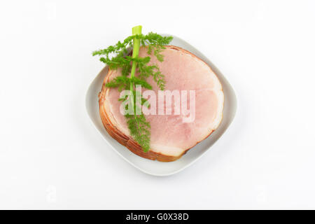 Pila di fette di prosciutto e aneto sulla piastra bianca Foto Stock