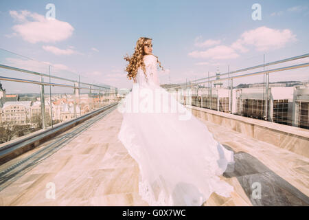 Bella Sposa in abito bianco ballando sul tetto contro lo sfondo di paesaggio Foto Stock