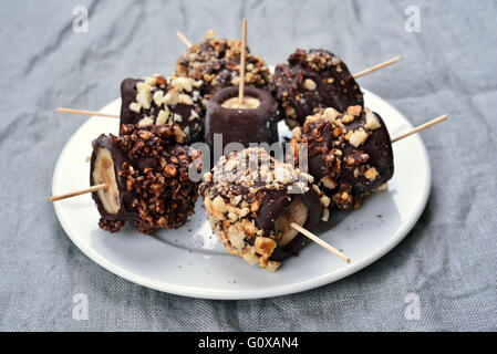 Banana surgelate ricoperte di cioccolato e arachidi Foto Stock