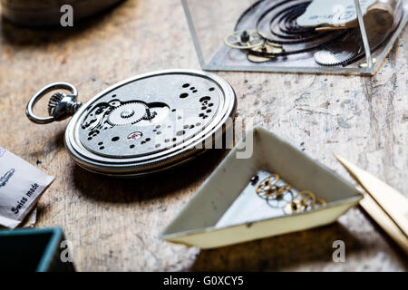 Primo piano della pocket watch meccanismo e clockworks sulla tavola di un orologiaio Foto Stock