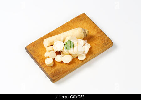 Tagliate a fette prezzemolo radice sul tagliere di legno Foto Stock