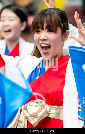 Giapponese Yosakoi dance festival. Ritratto, giovane donna che indossa il bianco, il rosso e il blu yukata, canto e ballo, la bocca spalancata, sembra molto felice. Foto Stock