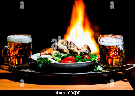 Due birre e salsicce con camino su sfondo Foto Stock