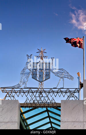 Stemmi e bandiera nazionale sulla sommità della moderna Casa del Parlamento a Capital Hill a Canberra, in atto. Cielo blu dietro national sym Foto Stock