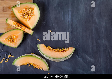 Fette di melone sul bordo di taglio sul bordo nero Foto Stock