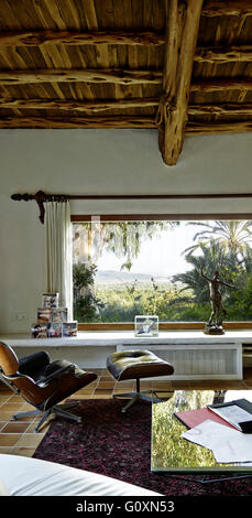 Country House, Ibiza. Un soffitto con travi in legno a vista. Una vista attraverso una finestra di vegetazione lussureggiante. Foto Stock