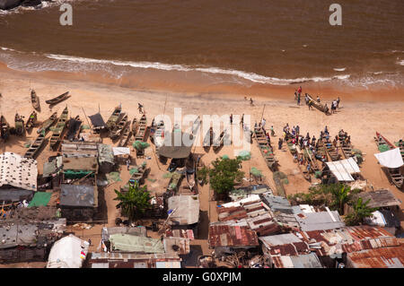 Persone, reti da pesca e canoe fare una per molto interessante la composizione della vita di tutti i giorni su una spiaggia a ovest di Monrovia Liberia. Foto Stock