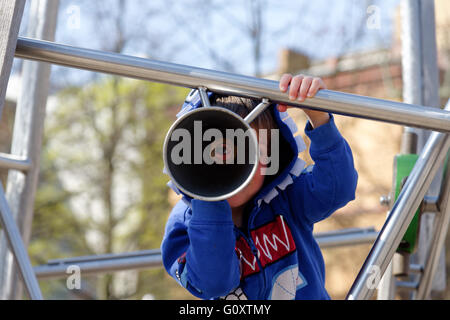 Un giovane ragazzo (4 anni) guardando attraverso un telescopio di riproduzione Foto Stock