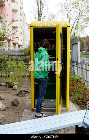 Un uomo con un libro BucherBoxx exchange booth a Berlino Foto Stock