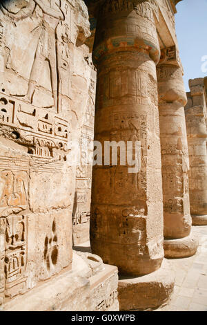 Dipinti egiziani, carving figure e geroglifici in colonne e una parete di pietra miliare tempio di Ramses o Ramesse III a Medinet Foto Stock