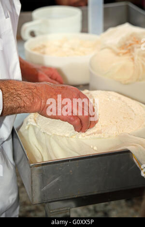 Mano di senior esperto casaro controlla la ruota di formaggio appena fatto nel caseificio di montagna Foto Stock