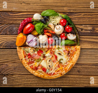 Pizza rustica tagliato a metà con ingredienti freschi. Servita su vintage tavolo in legno Foto Stock