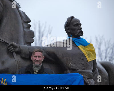 Kryvyi Rih, Ucraina - 29 novembre 2015: uomo detiene bandiera ucraine accanto al monumento al fondatore della città cosacco rih coperto con bandiera Foto Stock