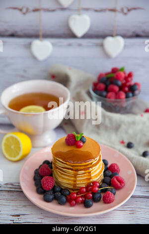 Pila di mirtillo frittelle su una piastra con mirtilli, lamponi e ribes Foto Stock