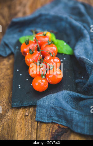 Arrosto di ciliegia pomodori a grappolo su lavagna Foto Stock