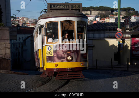 Il tradizionale vecchio tram numero 28 si inerpica su per una ripida e stretta strada di ciottoli di Chiado di Lisbona. Il Portogallo. Foto Stock