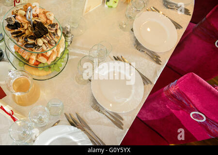 Tabella di nozze con piastre, forchette, coltelli, bicchieri, i cookie e le sedie rosse Foto Stock