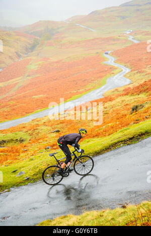 Rider Hardknott ascendente passare durante il Fred Whitton sfida, un 180km/112 miglia di corsa sportiva nel Lake District inglese Foto Stock