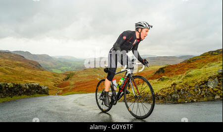 Rider Hardknott ascendente passare durante il Fred Whitton sfida, un 180km/112 miglia di corsa sportiva nel Lake District inglese Foto Stock