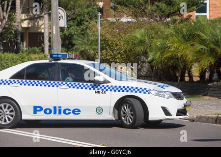 Agente di polizia che guida un'auto della polizia del nuovo Galles del Sud a Sydney, Australia, facendo un'inversione a U illegale su due linee bianche Foto Stock
