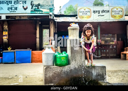 Una bambina che usa l'acqua da un punto di uscita alla periferia della città di montagna di Dhulikhel, Nepal. Foto Stock