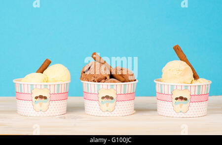 A tre differenti tipi di gelato fatto in casa in bicchieri di carta sul luminoso sfondo blu Foto Stock