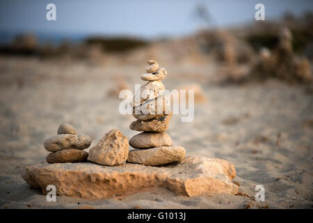 Spazio Zen. Pietre. Spiaggia di Ses Illetes, isole Baleari, Formentera, Spagna. Le luci di retroilluminazione nel tramonto con pietre con forme diverse. 'L'Alluvione' ('La Riada'), un unico spazio costruito con pietre dal tedesco Johannes Schultz. Foto Stock