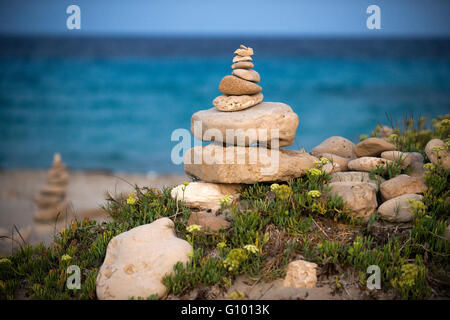 Spazio Zen. Pietre. Spiaggia di Ses Illetes, isole Baleari, Formentera, Spagna. Le luci di retroilluminazione nel tramonto con pietre con forme diverse. 'L'Alluvione' ('La Riada'), un unico spazio costruito con pietre dal tedesco Johannes Schultz. Foto Stock