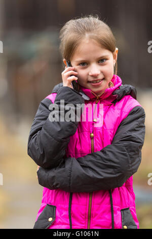 Funny bambina parlando al telefono, ritratto all'aperto. Foto Stock