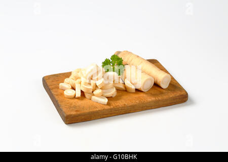 Tagliate a fette prezzemolo radice sul tagliere di legno Foto Stock