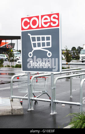 Un supermercato Coles carrello in una baia in posizione di parcheggio per i clienti contro un carrello segno Foto Stock