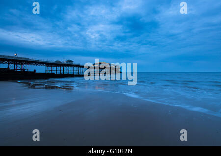 La sera Nuvoloso a Cromer Pier, Norfolk come il sole tramonta Foto Stock